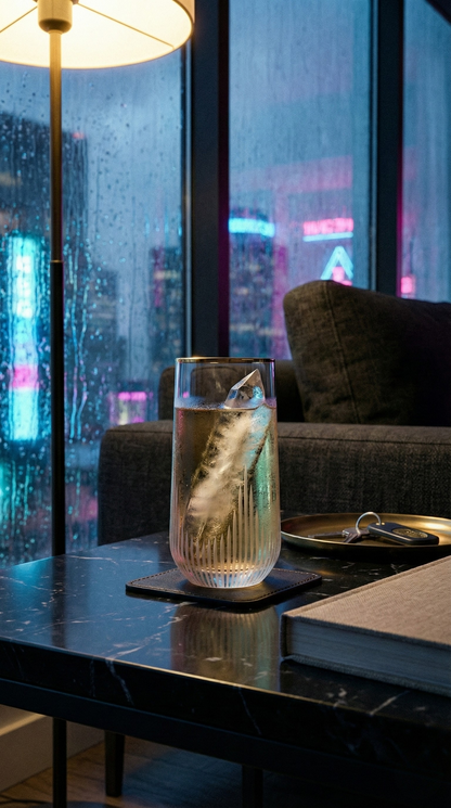 Ascend Highball Glass with a clear pour and citrus garnish in a rain-lit city lounge