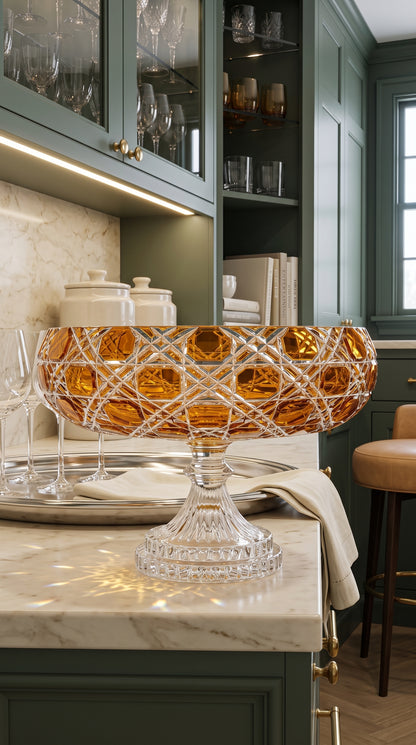 Verdura Sunlit Amber pedestal bowl on a pale kitchen island beneath glass-front cabinets