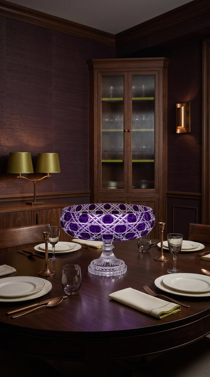 Verdura Regal Violet pedestal bowl centered on a dining table in a dark paneled room
