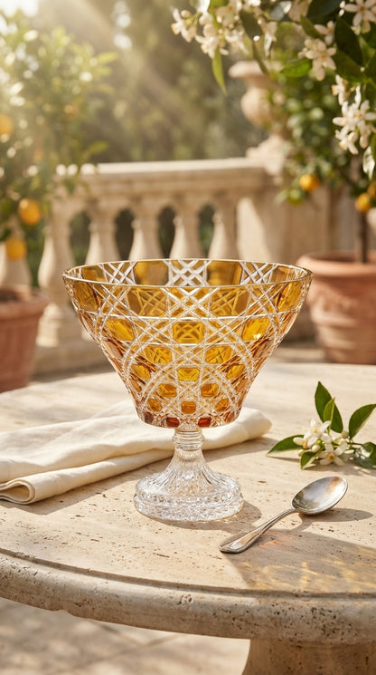 Sunlit Amber Verdura trumpet bowl on a stone terrace table beside an olive branch