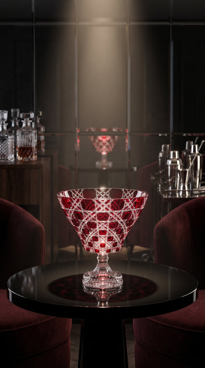 Crimson Red Verdura Trumpet Bowl on a round black table in a dark bar alcove.
