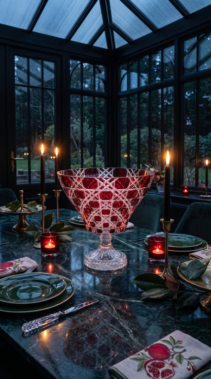 Crimson Red Verdura Trumpet Bowl centered on an evening dining table in a glass-walled room.